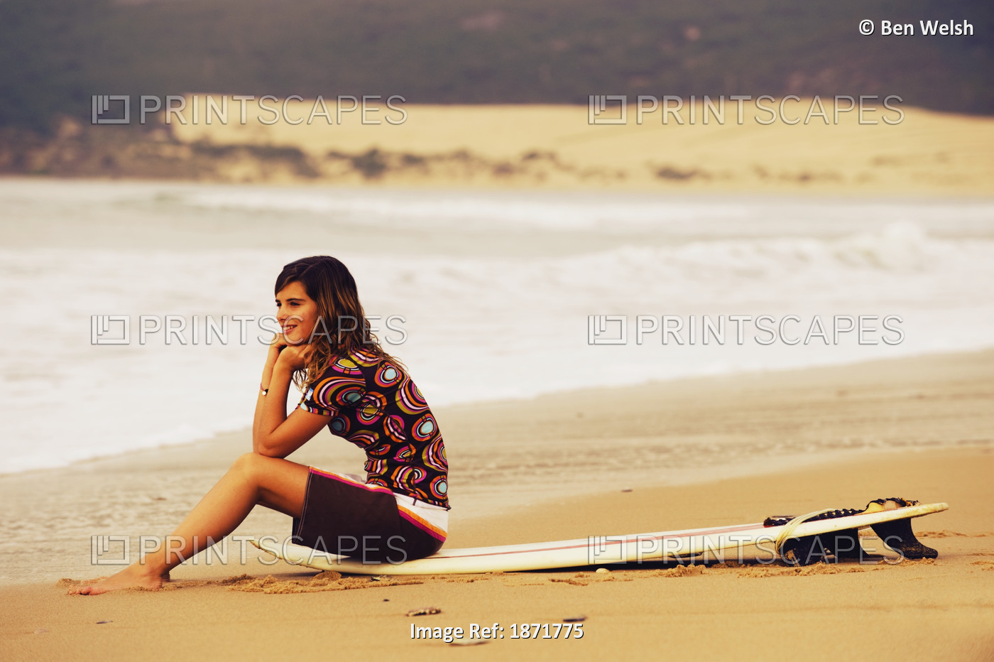 Young Woman Sitting On Her Surf Board On The Beach; Tarifa, Cadiz, Andalusia, ...