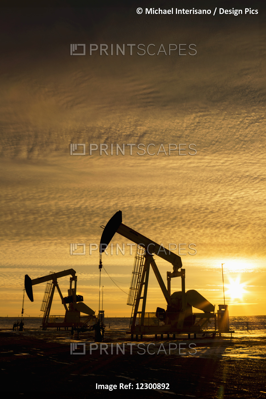 Silhouette Of Two Pump Jacks At Sunrise With Sun Burst And Colourful Clouds In ...